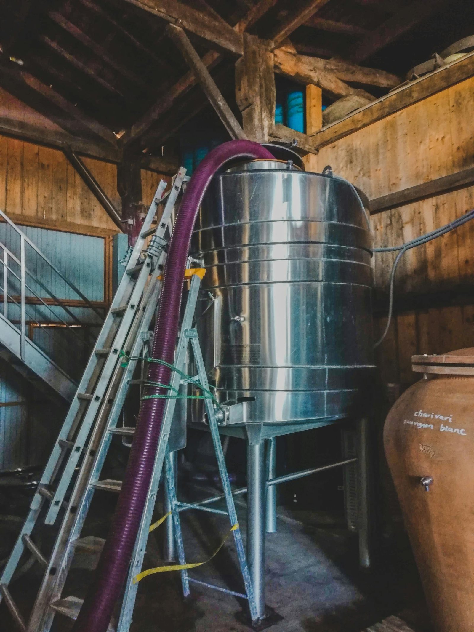 Industrial wine production equipment in a Bordeaux winery cellar.
